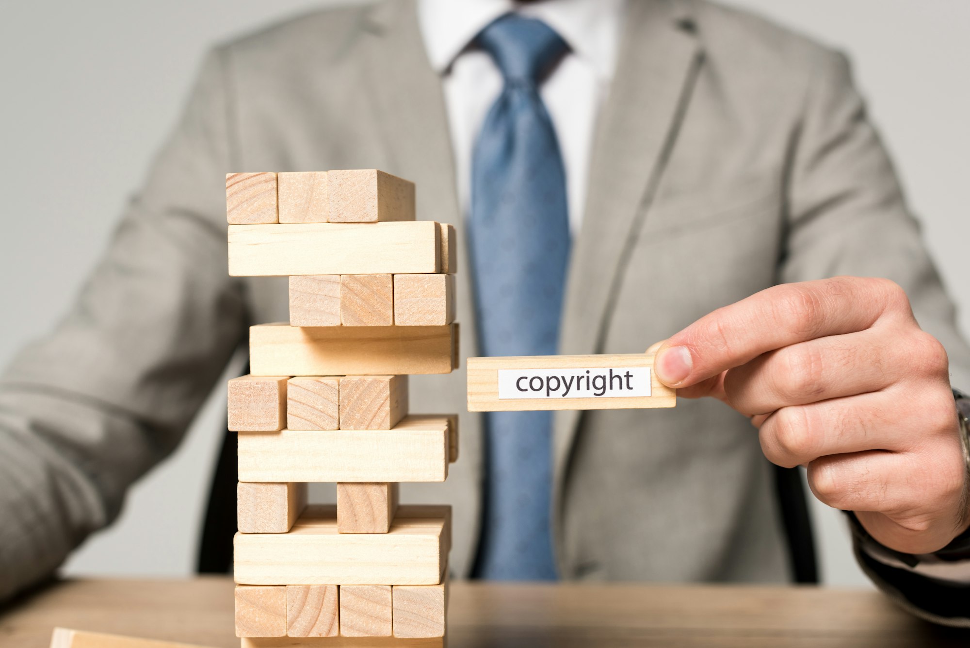 partial view of businessman holding wooden block with copyright inscription isolated on grey