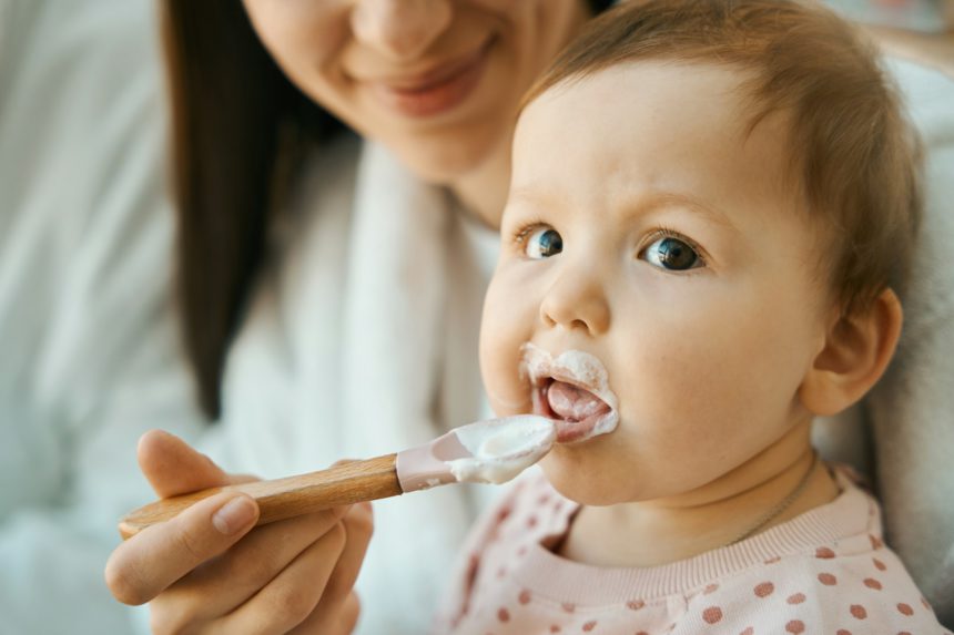 Smiling woman feeding a small child with a small spoon